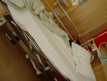 An empty hospital bed with green sheets